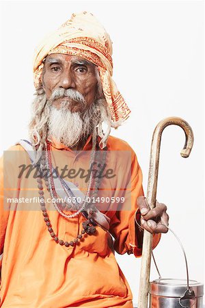 Portrait of a sadhu holding a cane and a utensil