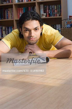 Portrait of a young man lying on the floor of a library and thinking