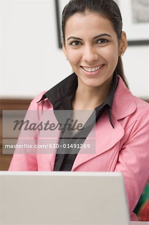 Portrait of a young woman sitting in front of a laptop and smiling