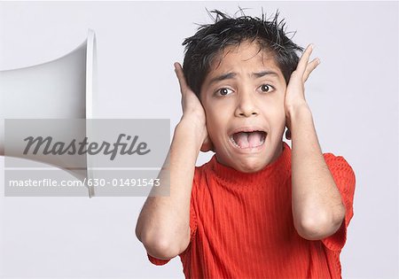 Portrait of a boy covering his ears with his hands