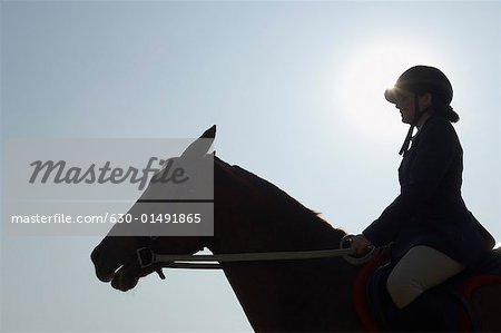 Silhouette of a female jockey riding a horse