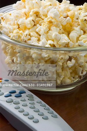 Close-up of a remote control and popcorn in a bowl