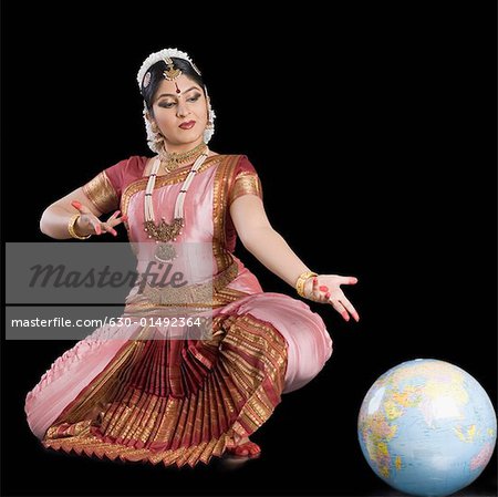 Young woman performing Bharatnatyam and gesturing towards a globe
