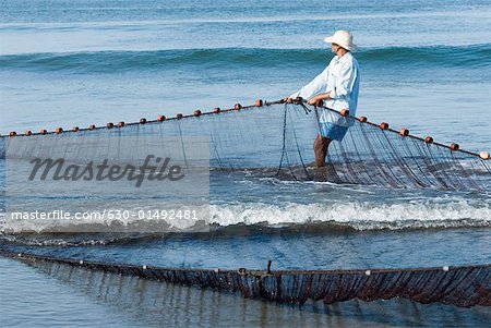 Side profile of a man pulling a fishing net on the beach, Morjim