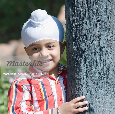 Close-up of a boy leaning against a tree trunk and smiling