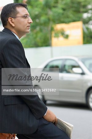 Side profile of a businessman holding a newspaper and thinking