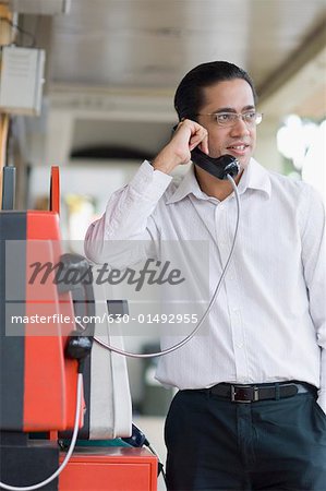 Mid adult man talking on a pay phone