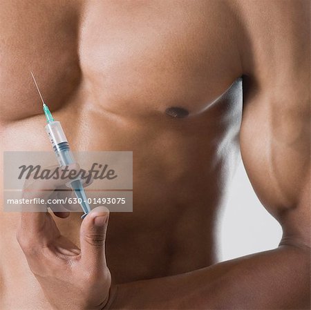 Mid section view of a young man holding a syringe against his chest
