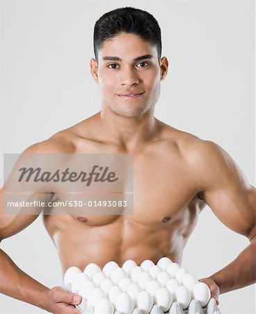 Portrait of a young man holding a carton of eggs