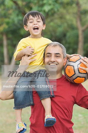 Mid Adult Man Carrying His Son On His Shoulder And Holding A Soccer Ball Stock Photo Masterfile Premium Royalty Free Code 630 01708072