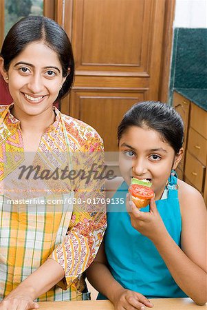 Portrait of a mid adult woman smiling beside her daughter eating a sandwich