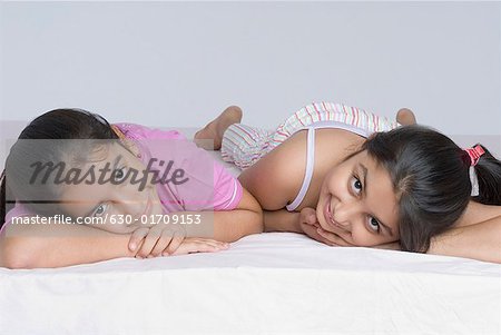 Portrait of two girls lying together on the bed and smiling