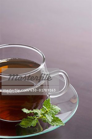 Close-up of a cup of herbal tea with mint leaf in a saucer