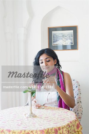 Young woman sitting in a restaurant and holding a glass of lemon juice