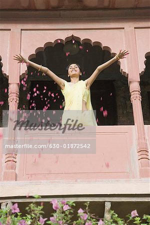 Low angle view of a young woman spreading petals from the balcony of a fort, Neemrana Fort Palace, Neemrana, Alwar, Rajasthan, India