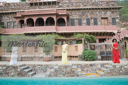 Three young women standing at the poolside of a palace, Neemrana Fort Palace, Neemrana, Alwar, Rajasthan, India
