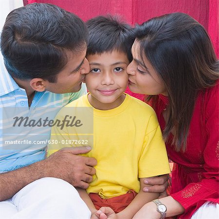 Mid adult couple kissing their son