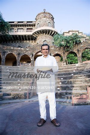 Portrait of a mid adult man holding a plate of powder paint, Neemrana Fort Palace, Neemrana, Alwar, Rajasthan, India