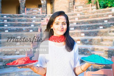 Portrait of a mid adult woman holding plates of powder paint and smiling, Neemrana Fort Palace Neemrana, Alwar, Rajasthan, India