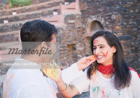 Close-up of a mid adult couple applying powder paint on each other's face