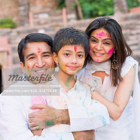 Mid adult couple with their son celebrating holi