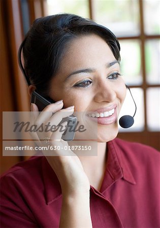 Close-up of a businesswoman wearing a headset and talking on a mobile phone and smiling