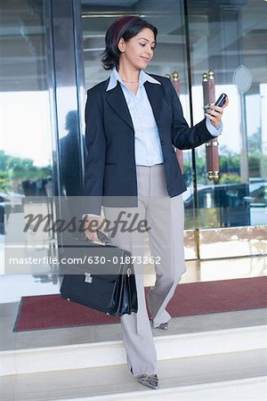 Businesswoman walking down steps and looking at a mobile phone