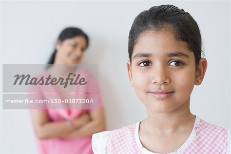 Close-up of a girl smirking with a mid adult woman standing in the background