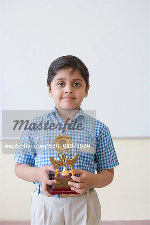 Portrait of a schoolboy holding a trophy and smiling