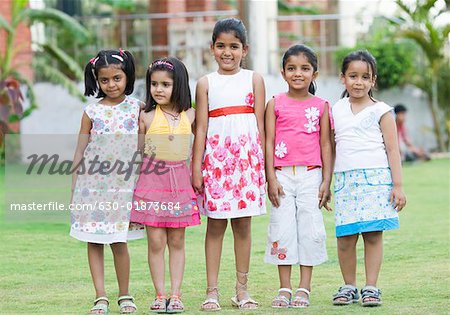 Five girls standing in a lawn and smiling