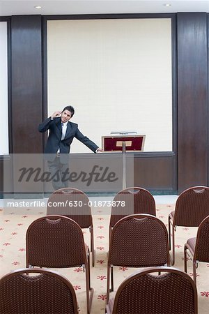 Businessman standing at a lectern and talking on a mobile phone