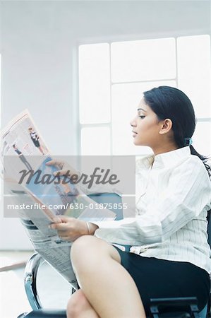 Businesswoman sitting at an airport and reading a newspaper