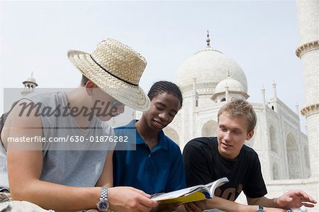 Three young men looking at a guidebook, Taj Mahal, Agra, Uttar Pradesh, India