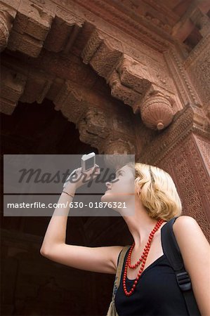 Low angle view of a young woman taking a picture with a digital camera, Taj Mahal, Agra, Uttar Pradesh, India