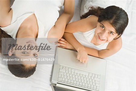 High angle view of a girl using a laptop on the bed beside her mother