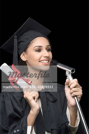 Close-up of a young female graduate holding a diploma and giving a speech