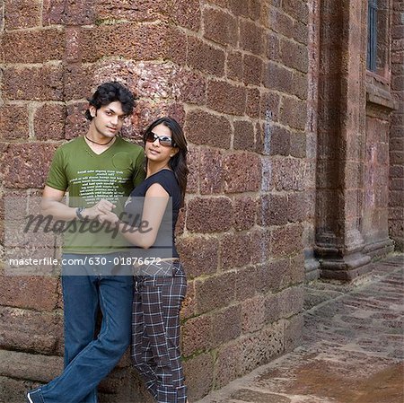 Young couple leaning against a wall, Goa, India