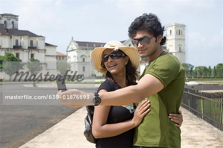 Side profile of a young couple taking a picture of themselves with a mobile phone, Se Cathedral Goa, India