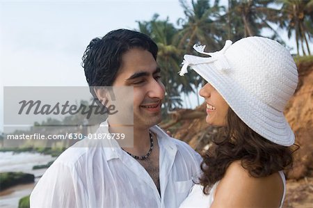 Close-up of a young couple looking at each other and smiling on the beach, Goa, India