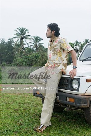 Young man leaning against a car and looking sad