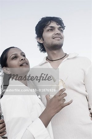 Young man standing with a young woman holding a glass of cocktail