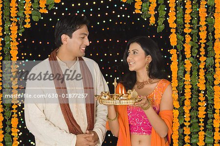 Young woman holding a diwali thali with a young man standing beside her