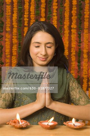 Young woman praying with oil lamps in front of her