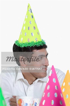 Mid adult man wearing a birthday hat and smiling