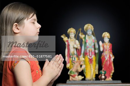 Side profile of a girl praying in front of a Hindu idol