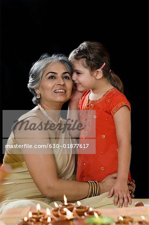 Girl whispering into her grandmother's ear