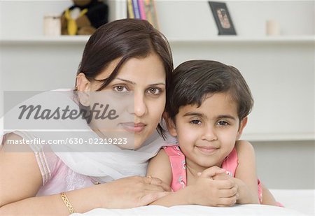 Portrait of a mid adult woman with her daughter lying on the bed