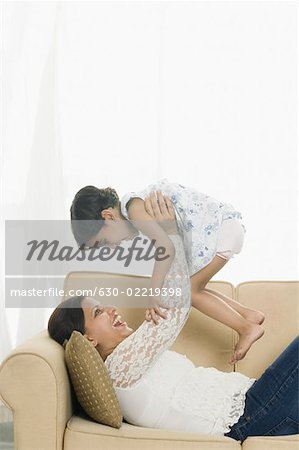 Side profile of a mid adult woman with her daughter playing on a couch