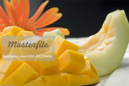 Close-up of mango slices and melon slices with a daisy flower