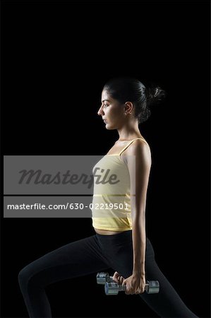 Side profile of a young woman exercising with dumbbells